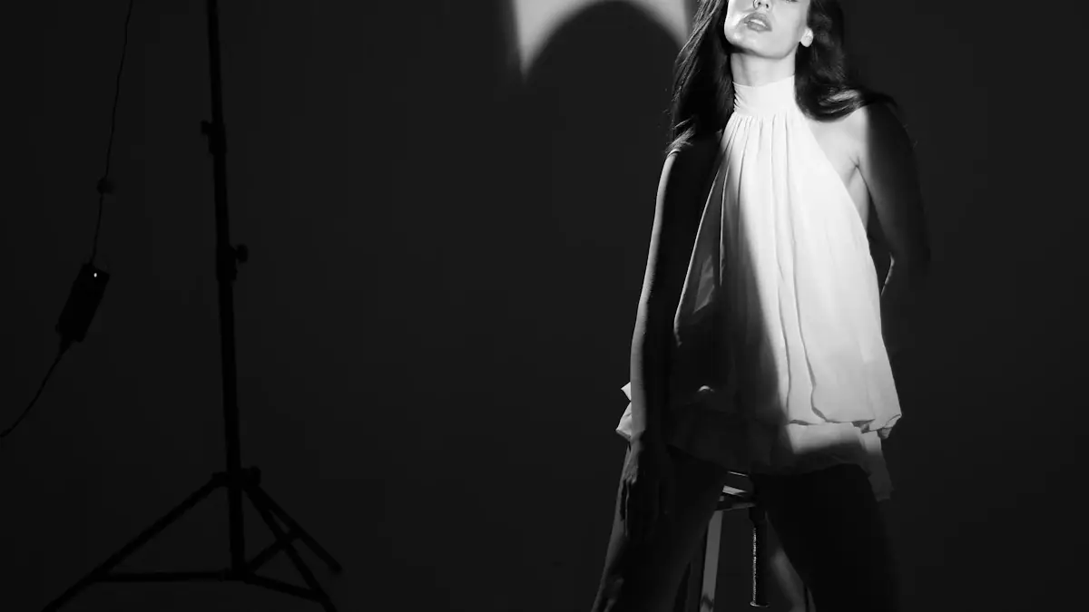 Black-and-white fashion studio photograph with a model and lighting equipment.